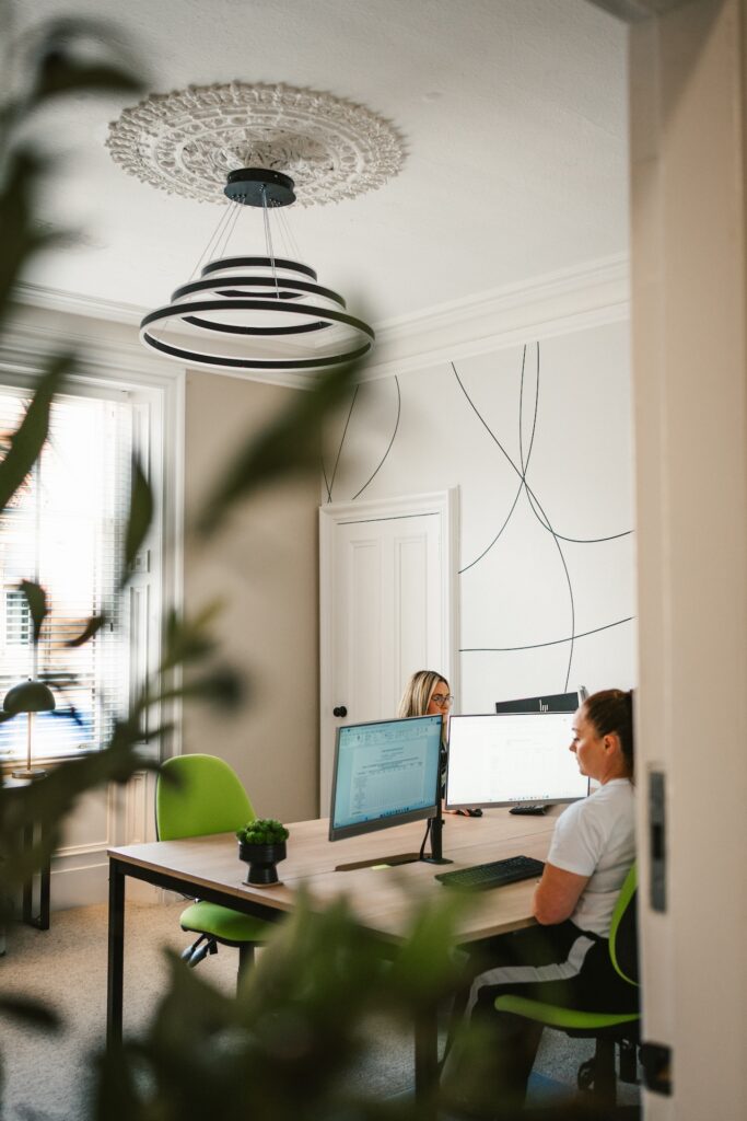 Modern office interior in Kilmarnock with two employees working at their desks, captured as part of natural business branding photography.
