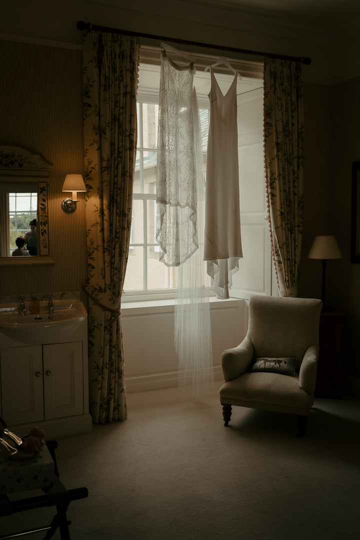 Close-up of the bride’s dress and veil hanging in the window at Dumfries House, Ayrshire.