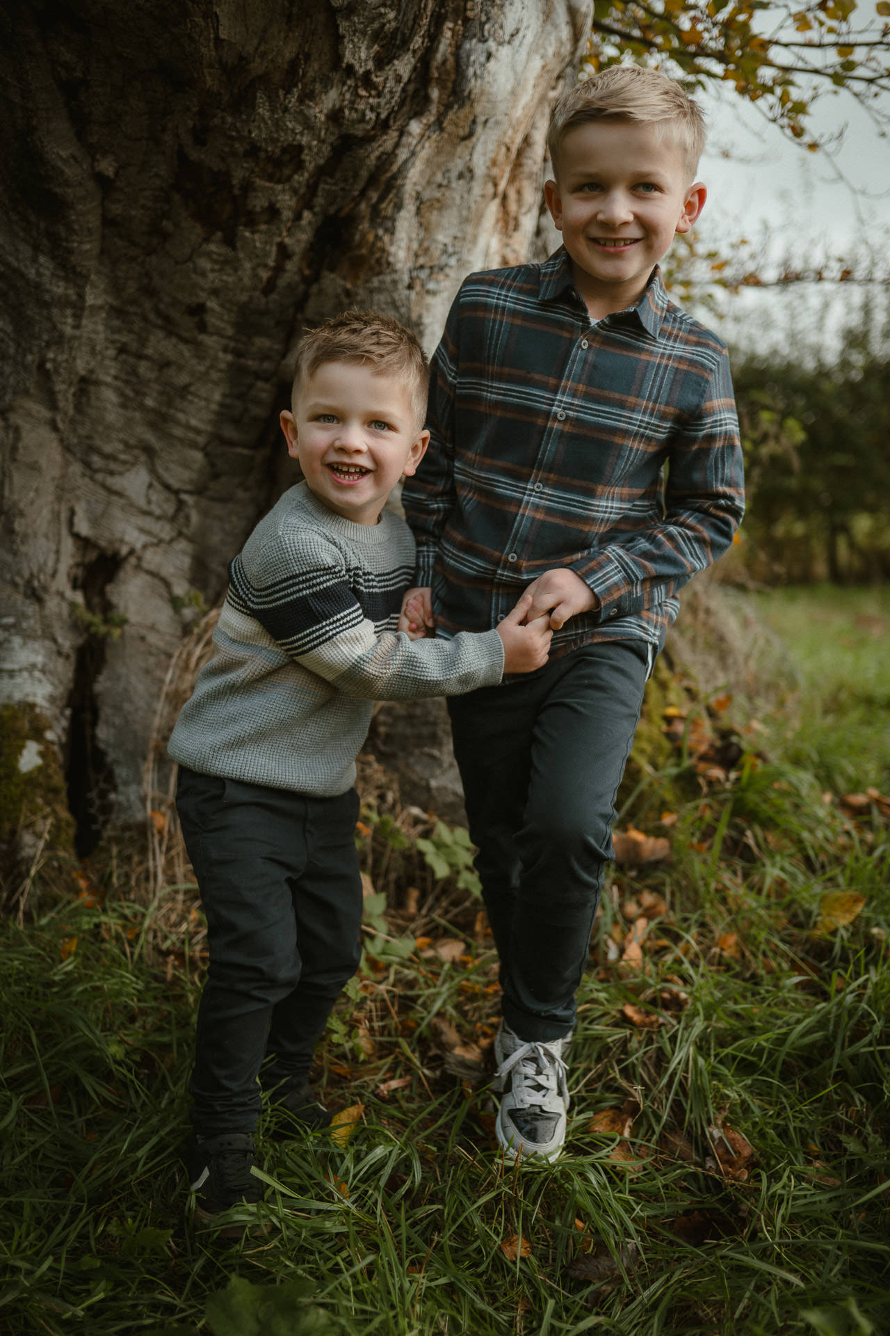 Two young brothers laughing together during a natural outdoor family photoshoot at Dumfries House in Ayrshire.