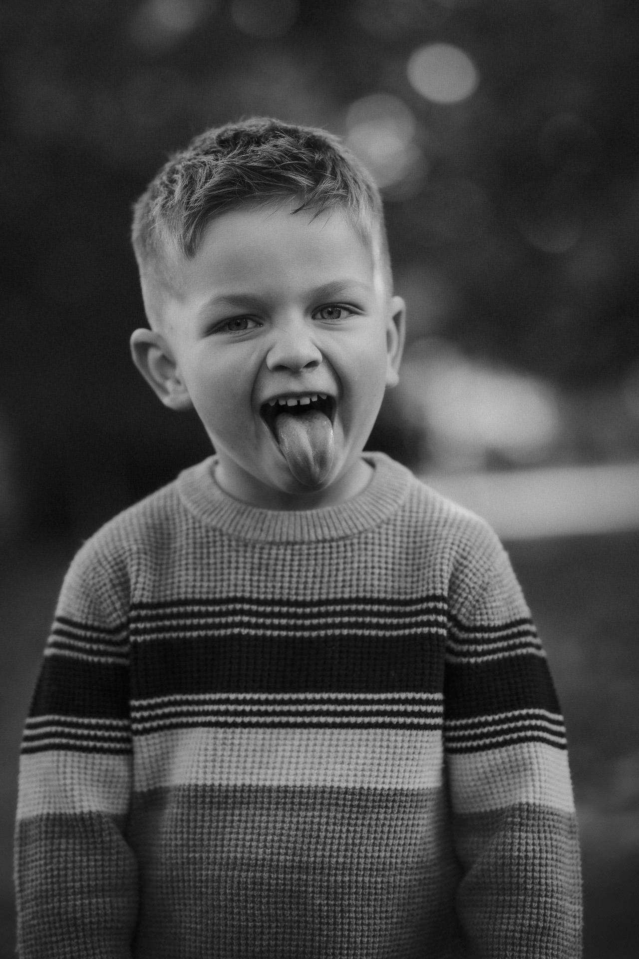 Natural family photoshoot in Ayrshire, Scotland, candid moment of a young boy laughing outdoors.