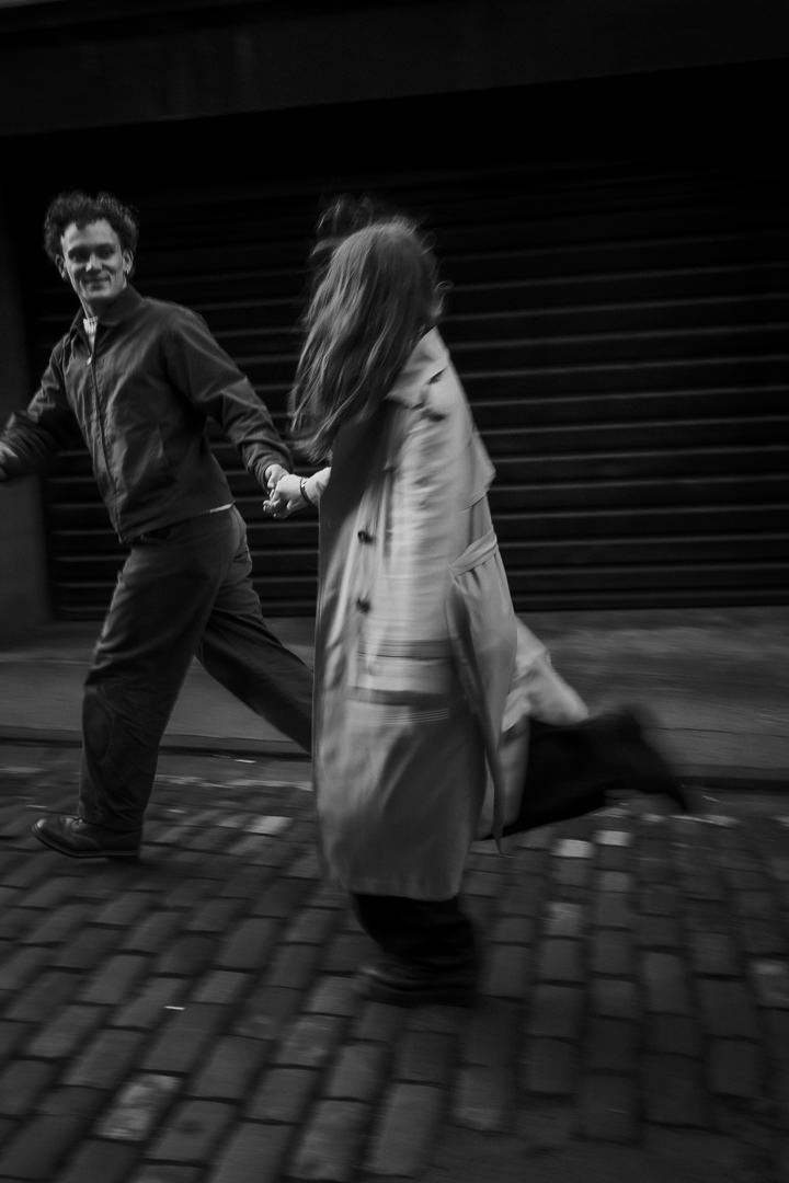 Engaged couple running in street.