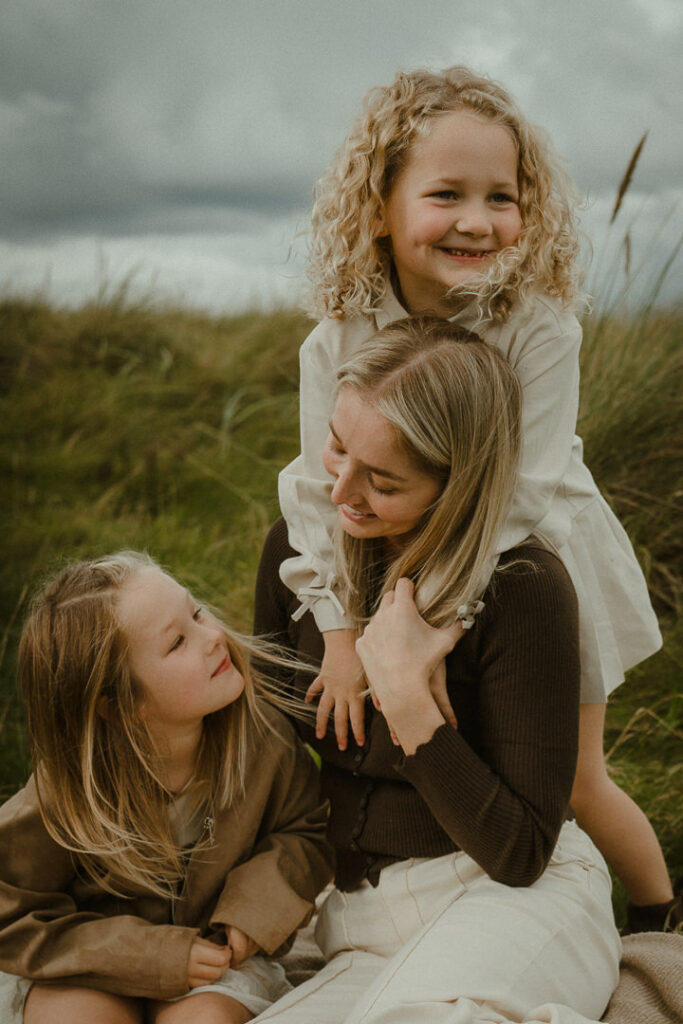 A close moment of a mother at the beach with her two daughters.