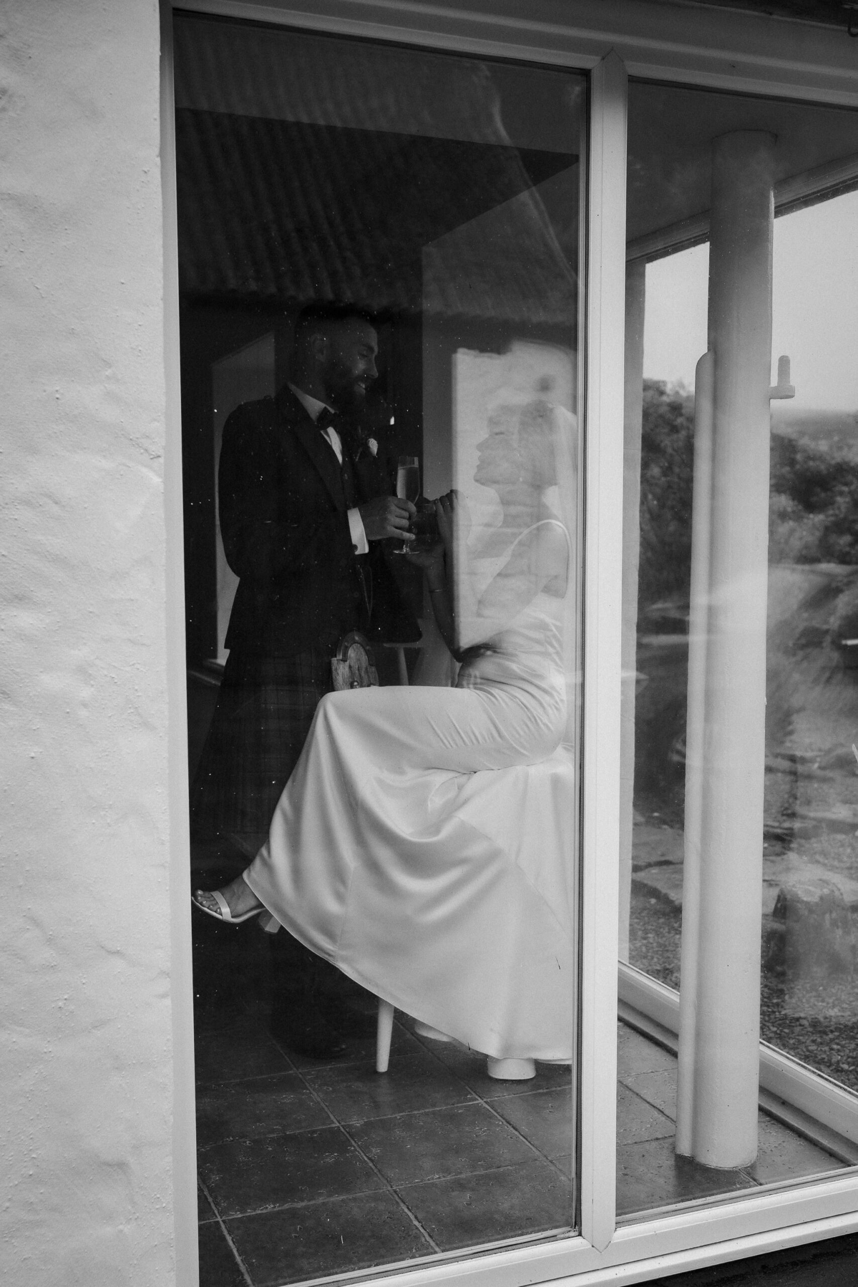 Bride and groom sharing a quiet moment through a window at an Ayrshire wedding