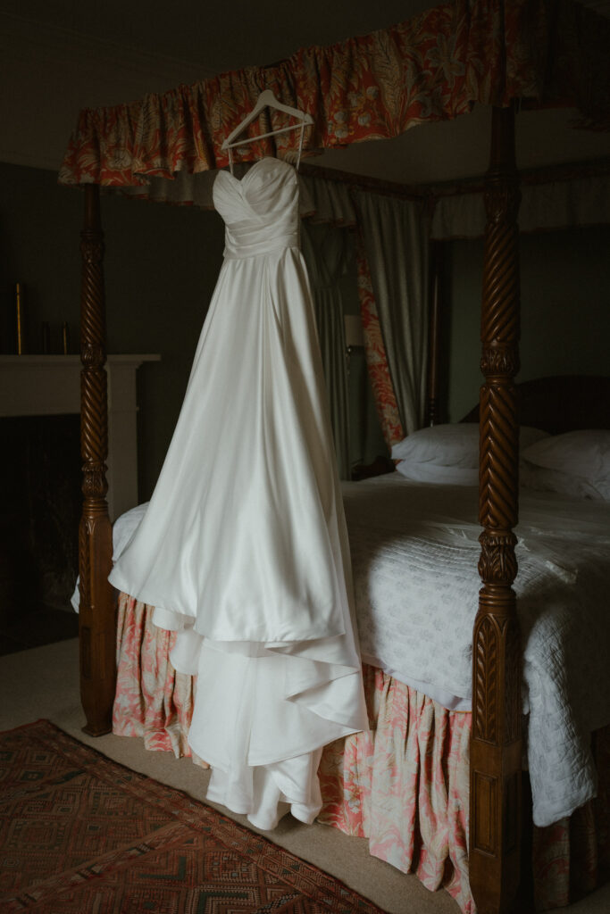 Wedding dress hanging in a bedroom before bridal preparations.