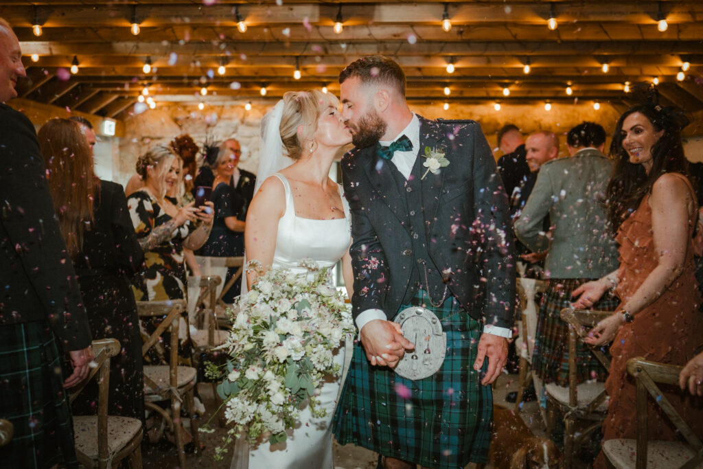 Bride and groom kissing during their confetti throw.