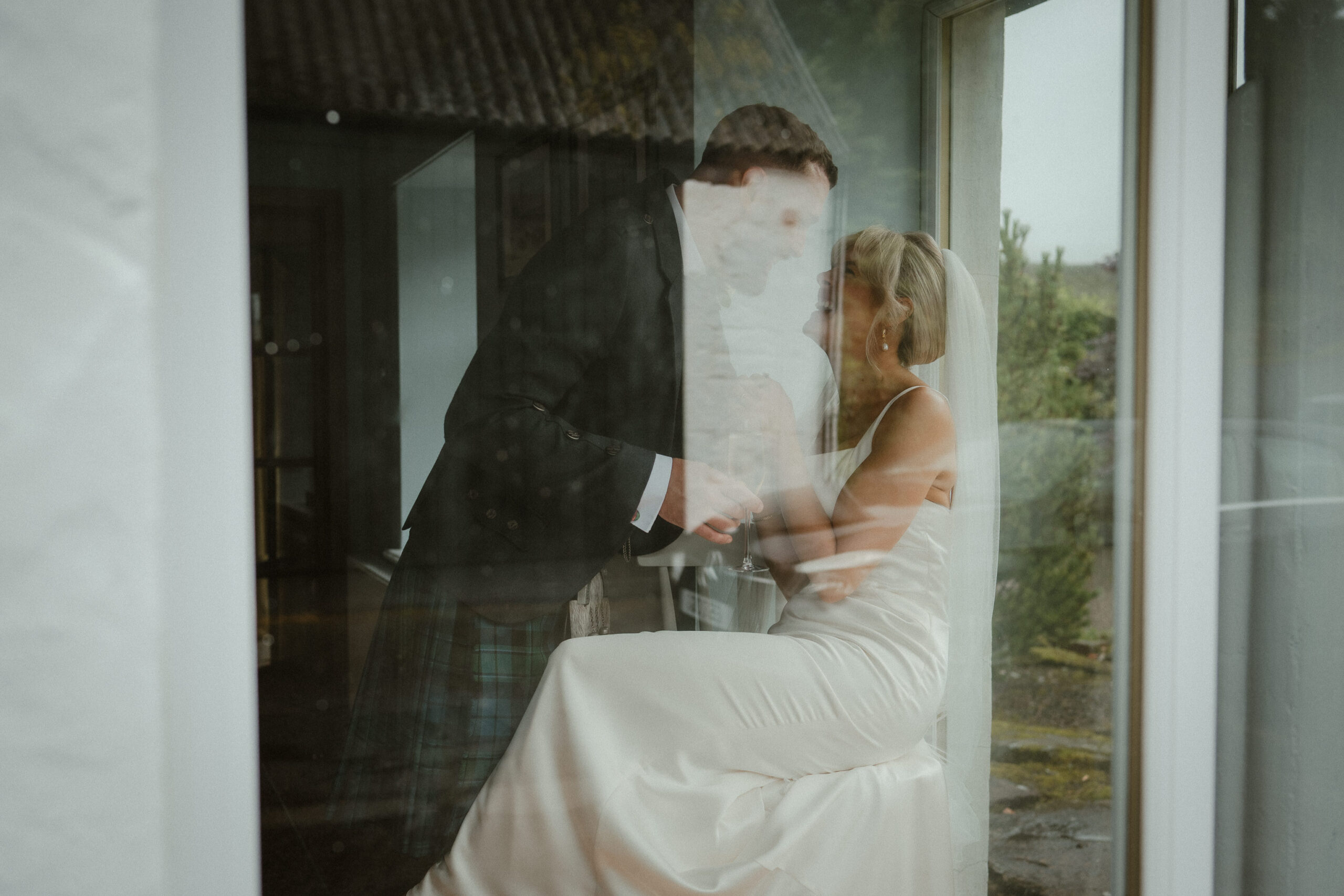 Bride and groom sharing a quiet moment through a window at an Ayrshire wedding