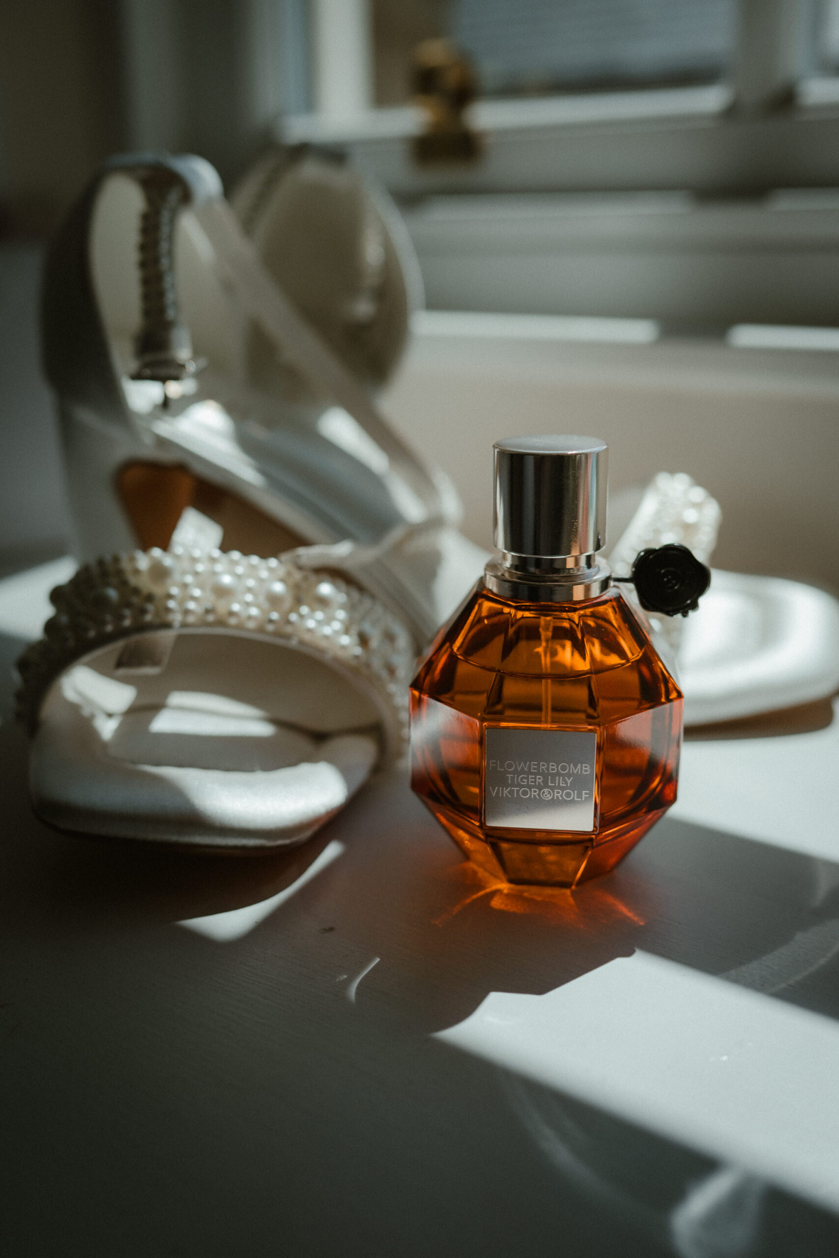 Bride's wedding shoes and perfume during morning preparations.